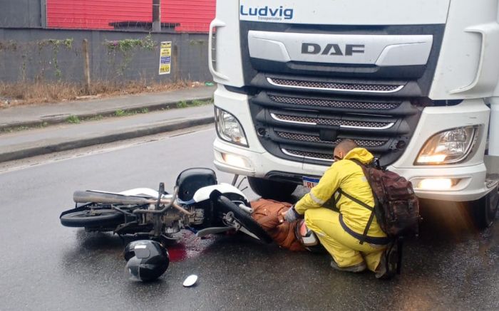 Motociclista sofreu lesões graves na perna após parar embaixo do caminhão (Foto: Leitor)